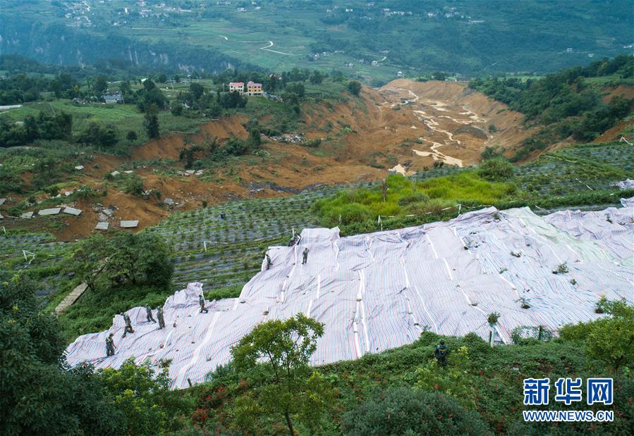 7月23日，抢险人员在恩施屯堡乡马者村山体滑坡现场进行铺设油布作业（无人机照片）。新华社记者 肖艺九 摄